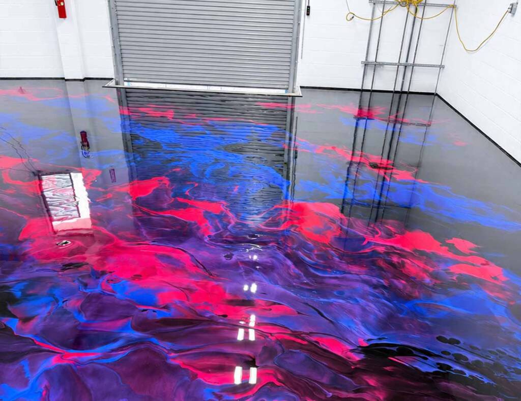 A vibrant and colorful pink, black and blue metallic epoxy floor in an industrial shop.